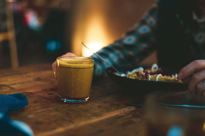 Midsection of person holding drink on table