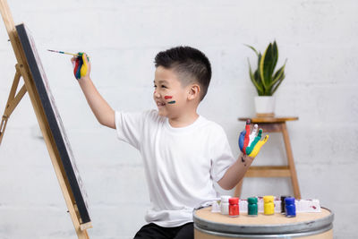 Boy holding ice cream standing against wall