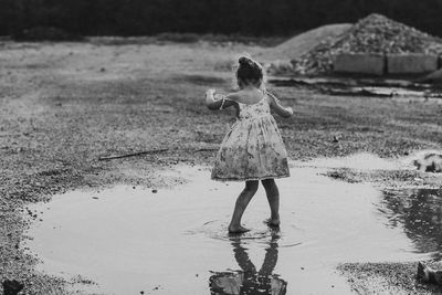 Full length of girl standing in puddle at beach
