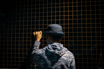 Rear view of man holding fence 