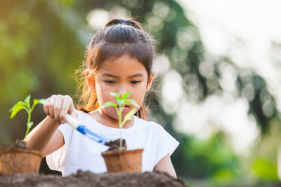 Cute girl planting sapling in garden