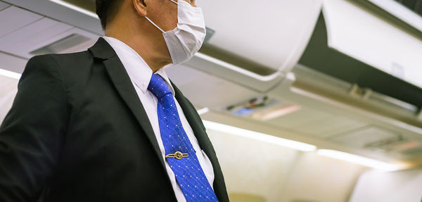 Midsection of man wearing mask standing at airplane