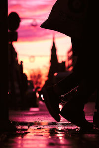 Low section of silhouette man standing in city during sunset