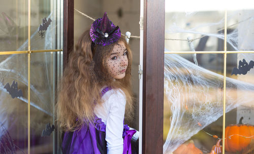 Portrait of young woman looking through window