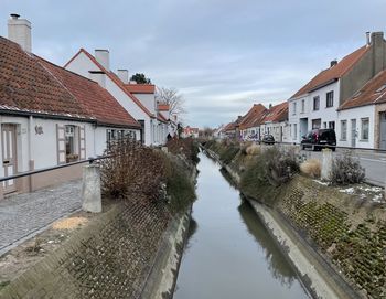 Canal amidst buildings against sky