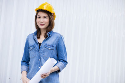 Portrait of smiling woman standing against wall