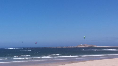 Scenic view of beach against clear blue sky