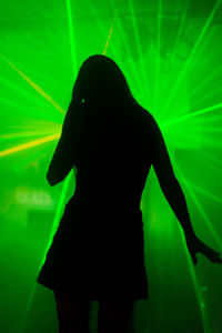 Rear view of silhouette woman standing at night