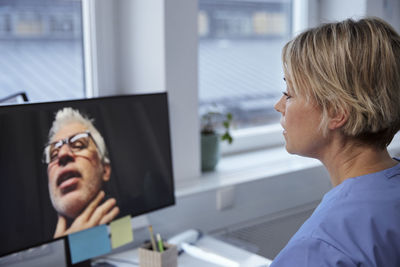 Female doctor having online consultation with senior patient