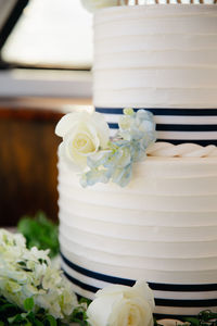 White wedding cake with blue hydrangea and roses decoration, two tiered marine themed desert.