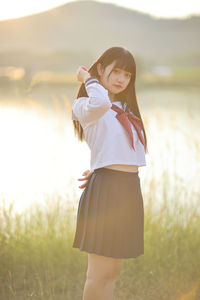 Side view of young woman standing on field