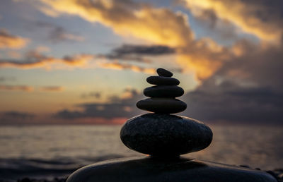 Stack of stones in sea during sunset