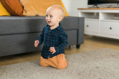 Side view of boy sitting on hardwood floor at home