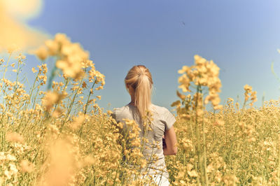 Rear view of woman standing on field against clear sky