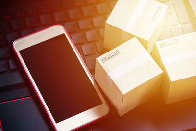 High angle view of cardboard boxes and phone on laptop