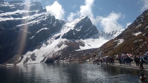 People at lakeshore by snowcapped mountains