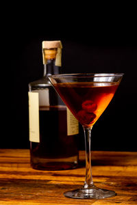 Close-up of cocktail in martini glass on table against black background