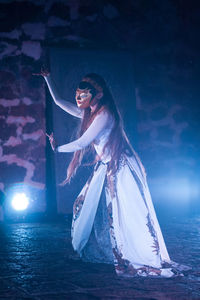 Woman wearing mask while dancing in dark