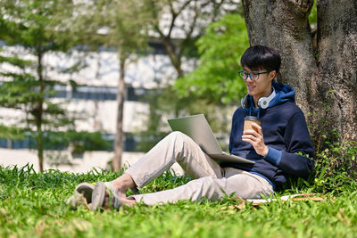 Young man using laptop while sitting on field