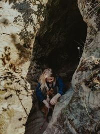 Young child girl on rock formation in cave with dog hiking