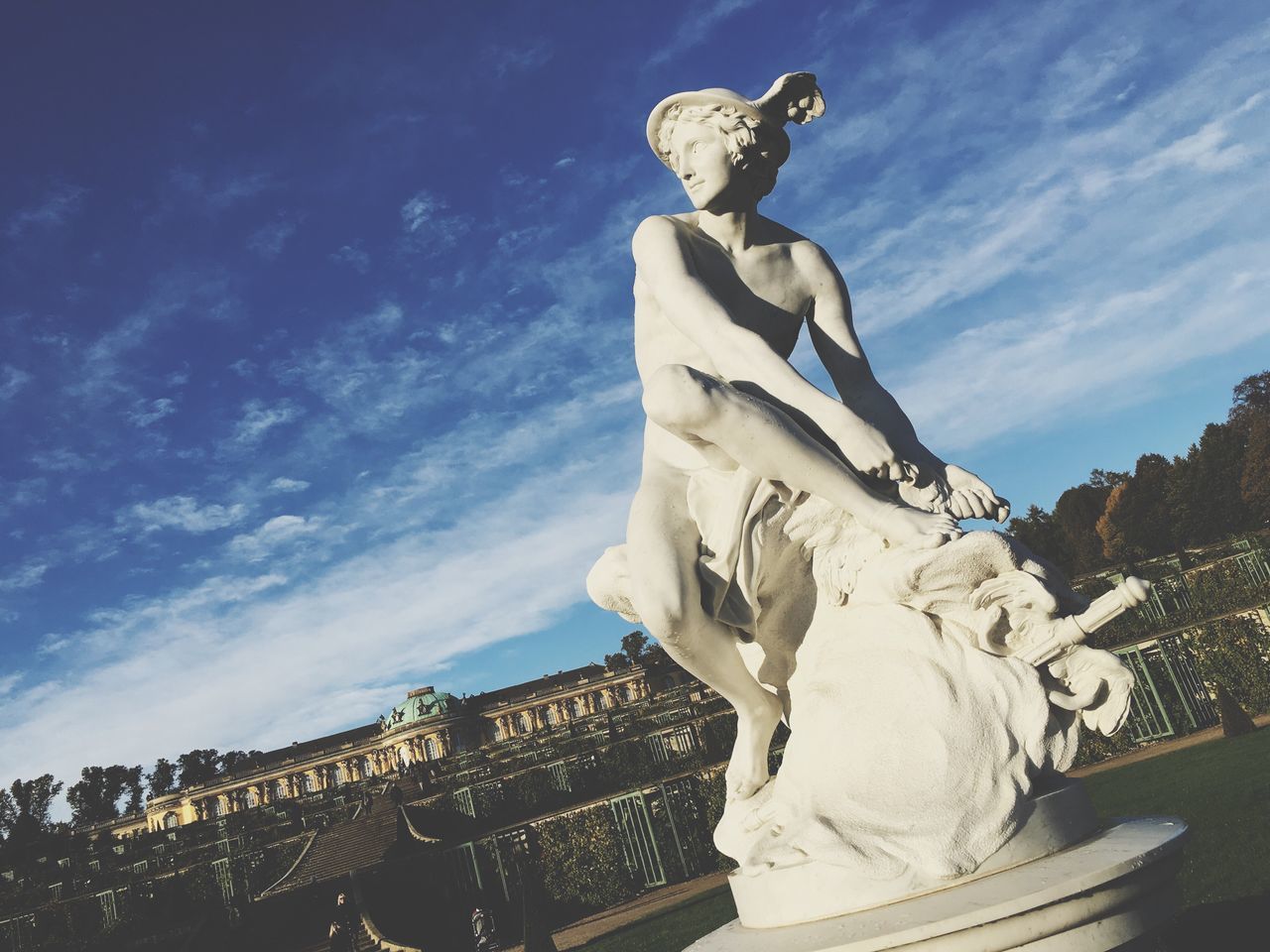 statue, human representation, sculpture, art and craft, art, low angle view, sky, creativity, travel destinations, monument, blue, city, famous place, cloud, outdoors, memories, pedestal, day, mythology, cloud - sky, large, tourism