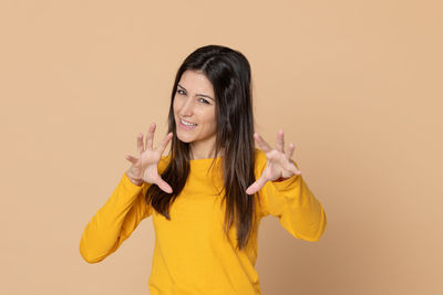 Portrait of a smiling young woman against yellow background