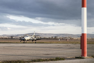 Airplane on airport runway against sky