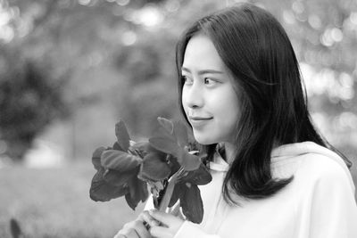 Young woman holding plant while looking away