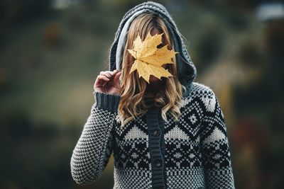 Woman holding leaf while standing outdoors