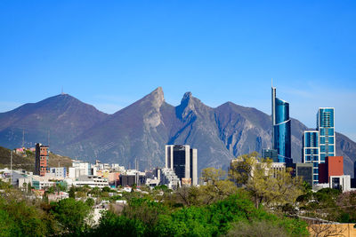 Buildings in city against clear blue sky