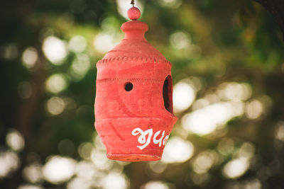 Close-up of red birdhouse hanging on tree