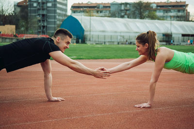 Side view of man and woman exercising on sports track