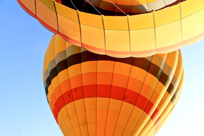 Low angle view of orange hot air balloons against clear sky