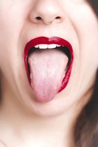 Cropped image of woman with red lipstick sticking out tongue