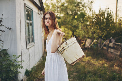 Portrait of woman holding bucket while standing outdoors