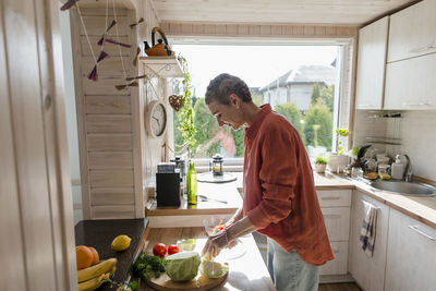 Woman preparing salad in kitchen at home