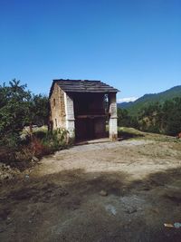 Old house on field against clear blue sky