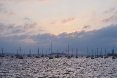 Sailboats in sea against sky during sunset