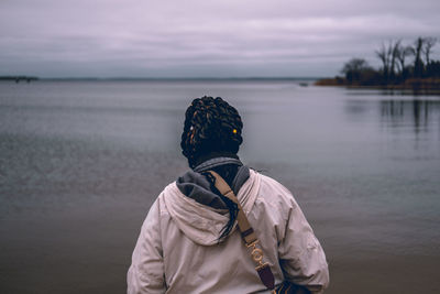 Rear view of woman standing by lake