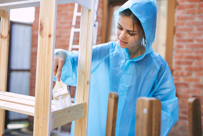 Portrait of young woman sitting on wooden wall