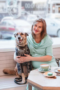 Portrait of smiling pregnant caucasian women with her dog in cafe. pregnant lifestyle.