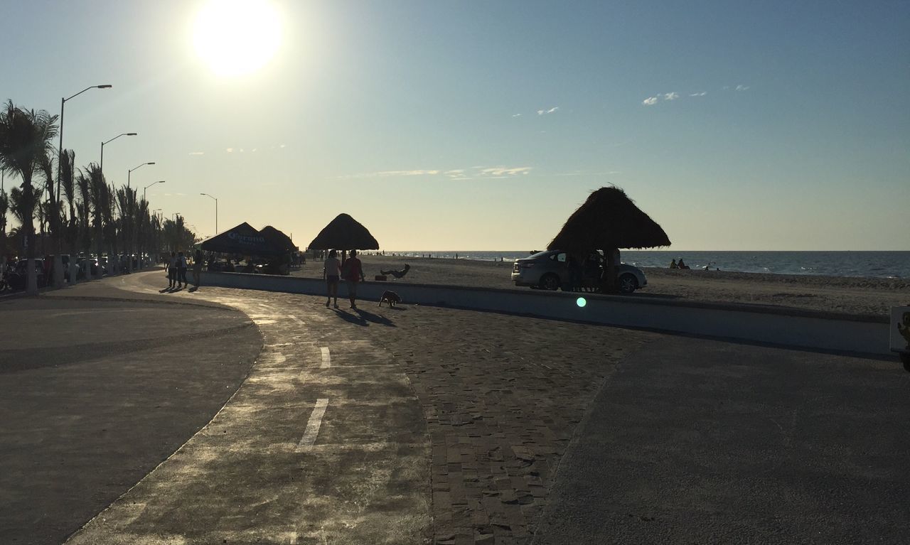 sea, horizon over water, beach, water, sky, sunlight, sun, shore, the way forward, silhouette, tranquility, incidental people, tranquil scene, sand, clear sky, scenics, road, sunbeam, nature, shadow