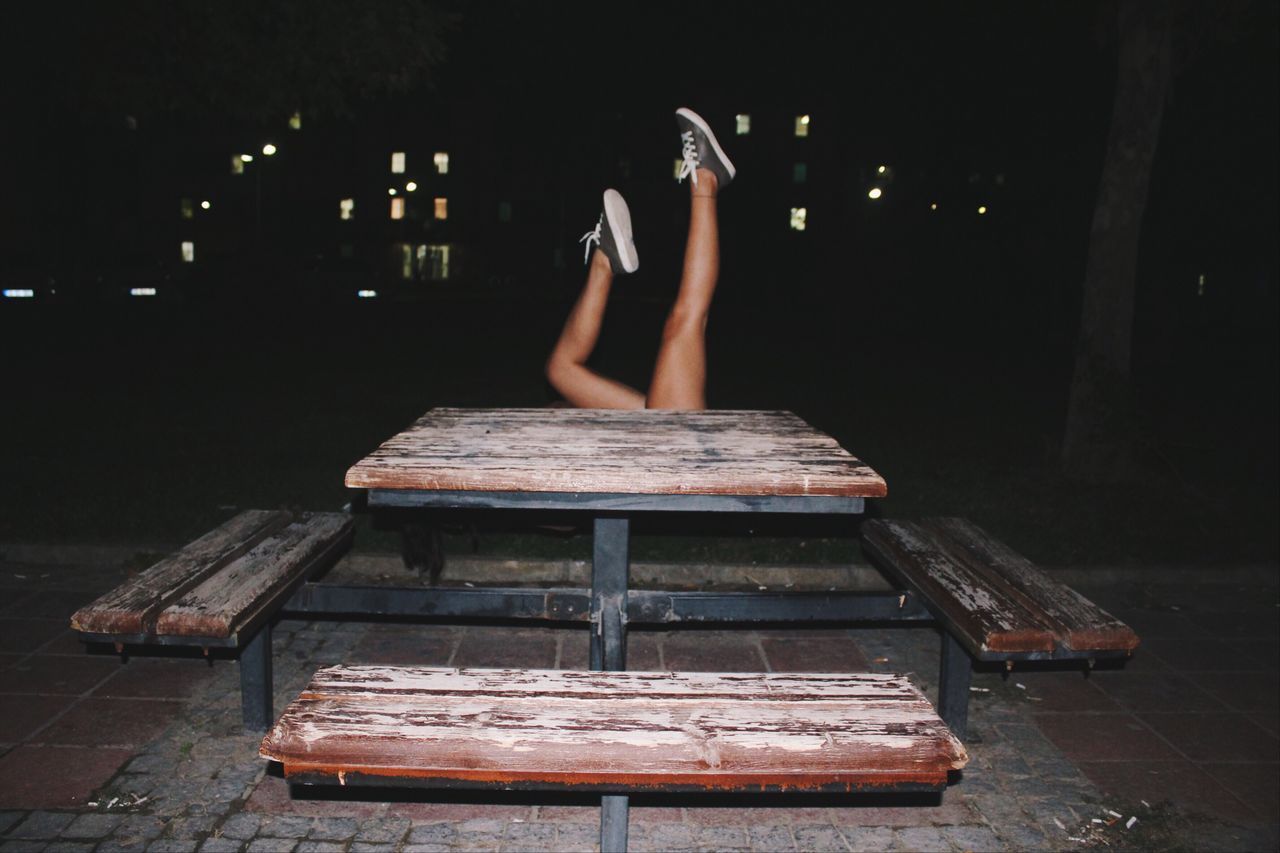 Woman lying with feet up by bench at night