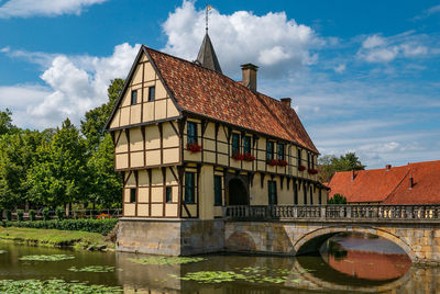 Arch bridge over river by buildings against sky