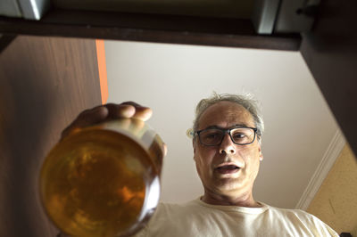 Mature man with grey hair picking up a bottle from the bar cabinet at home