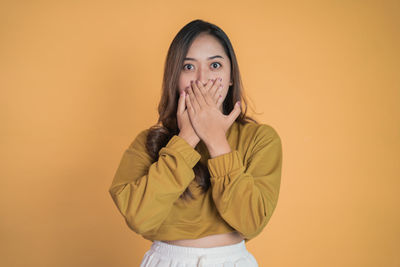 Young woman standing against yellow background