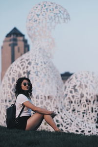 Side view portrait of woman sitting against sculpture