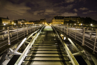 Illuminated bridge in city against sky at night