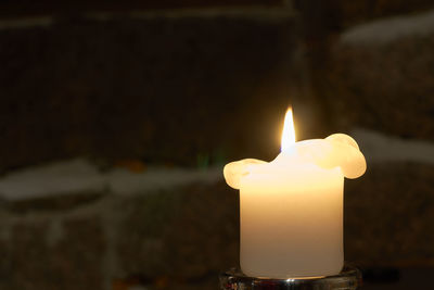 Close-up of lit candle in darkroom