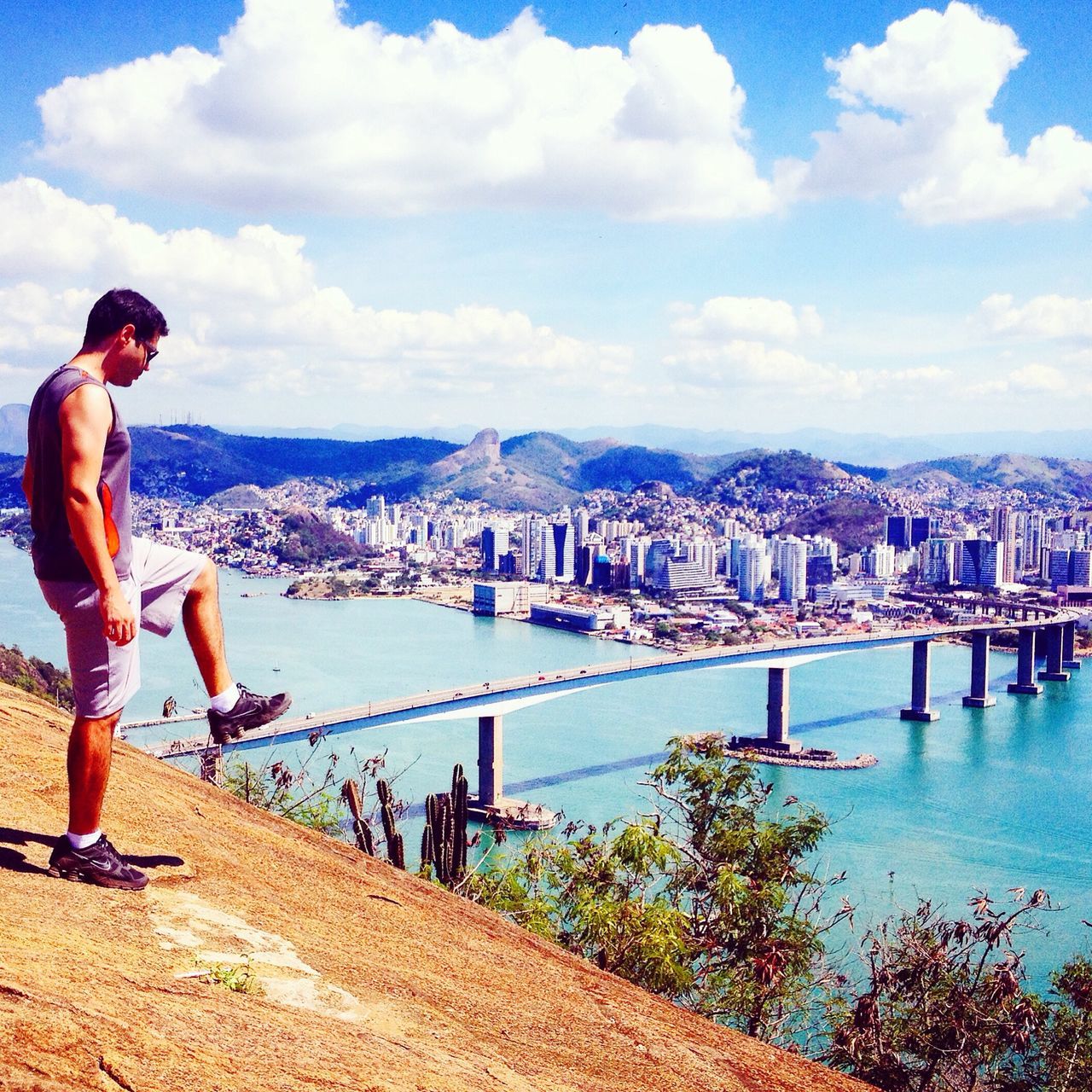 architecture, built structure, water, sky, river, bridge - man made structure, building exterior, railing, lifestyles, mountain, city, leisure activity, connection, cloud - sky, cloud, men, cityscape, rear view